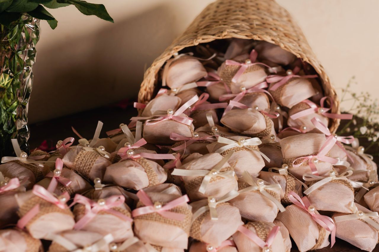 Charming wedding favors wrapped in burlap and pink ribbons, arranged in a rustic basket setting.